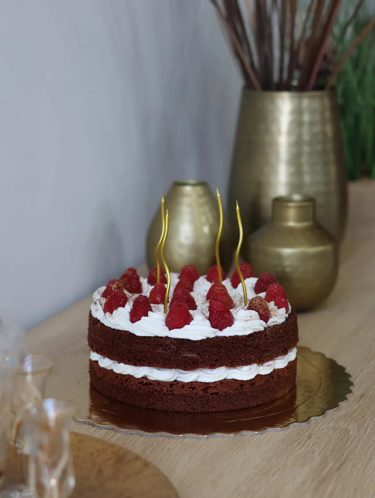 Bolo naked de chocolate e framboesas com vasos dourados