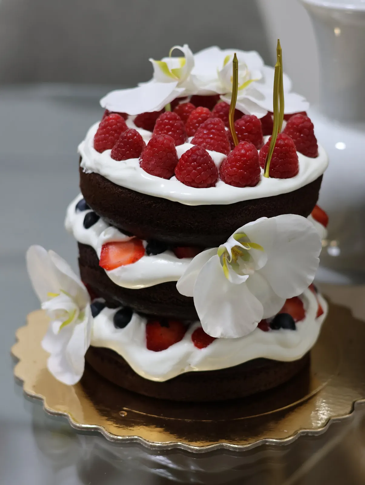 Bolo naked de chocolate com framboesas e orquídeas brancas