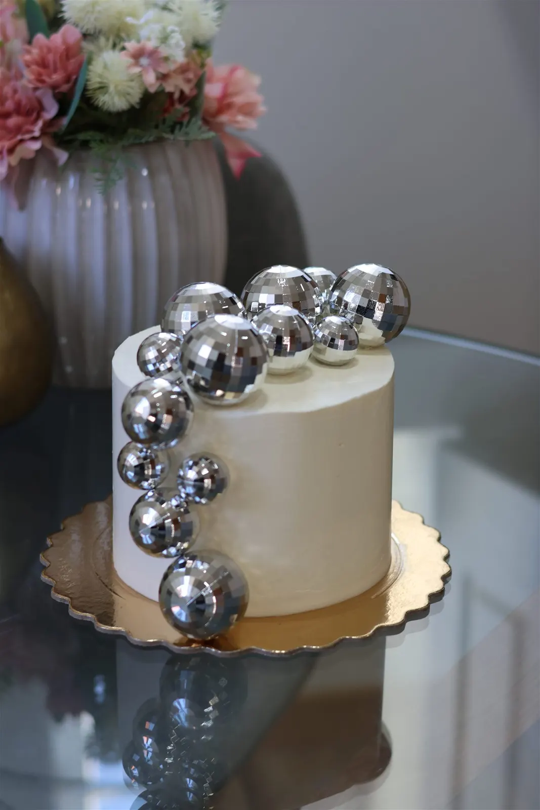 Bolo branco com bolas de espelhos prateadas